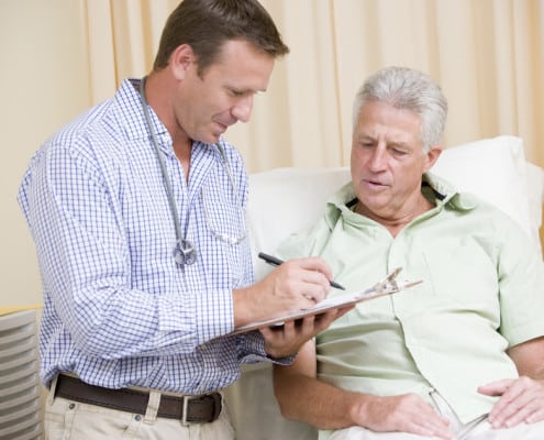 Physician checking a chart and speaking to a senior patient