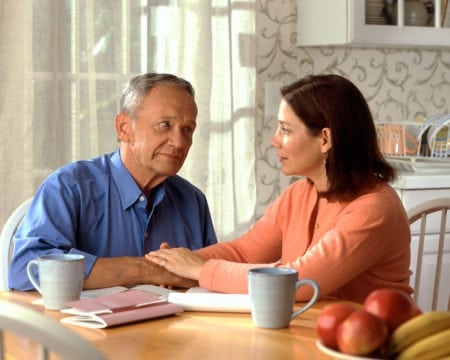 Senior man and family member having discussion at table